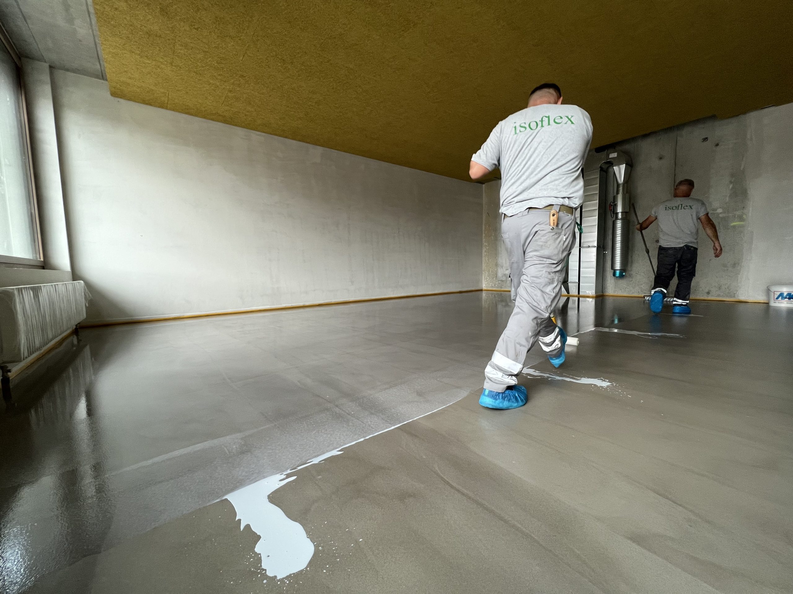 Arbeiter der isoflex bautechnik AG beschichten einen Boden.